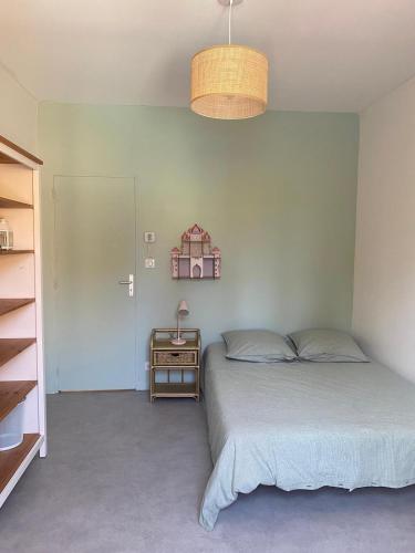 une chambre avec un lit et une table avec une lampe dans l'établissement maison familiale climatisée piscine, à Blanquefort