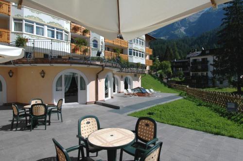an outdoor patio with tables and chairs and a building at Residence Pez Gajard in San Martino di Castrozza