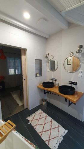 a bathroom with two sinks and mirrors on the wall at La Maison de Judith Chambres d hôtes in Orthez