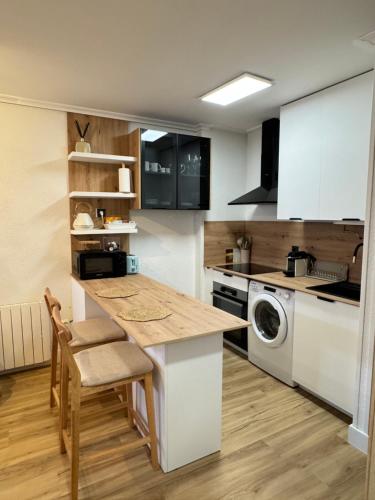 eine Küche mit einer Theke, einem Tisch und einem Geschirrspüler in der Unterkunft Apartamento Aquí Mismo en playa de Somo Garaje in Somo