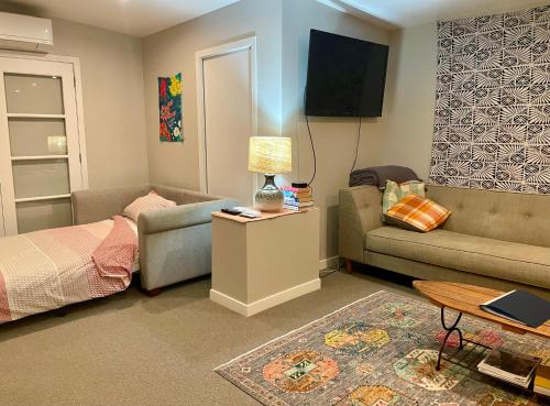 a small living room with a couch and a bed at Studio Wing in Saint Heliers in Auckland