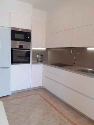 a white kitchen with white cabinets and a sink at Algarve's Holiday Home with Sea View in Ferragudo