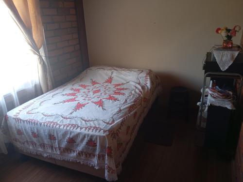 a bedroom with a bed with a red and white quilt at Gardenias Suites Ambuquí Valle de la Eterna Juventud in Hacienda Opote
