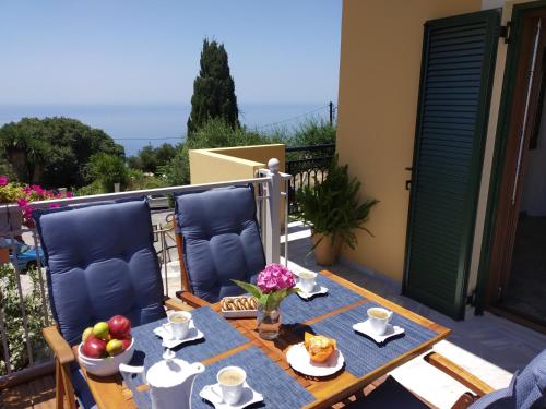 a table with food and fruit on a balcony at Kontis Apt 1 in Pelekas