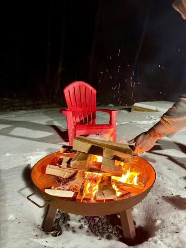 a red chair around a fire pit in the snow at The Mont Haus - Minutes to Mt Snow & Stratton! in Wardsboro