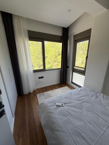 a bedroom with a bed and two windows at Canyon Villa Göynük Kemer Antalya with Pool in Antalya