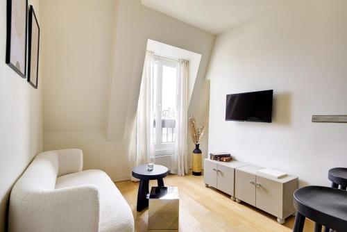 un salon avec un canapé et une télévision sur un mur dans l'établissement La vie du marais, à Paris