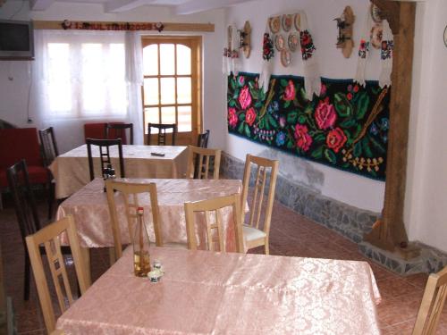 a dining room with tables and a painting on the wall at Casa Muntean in Vadu Izei