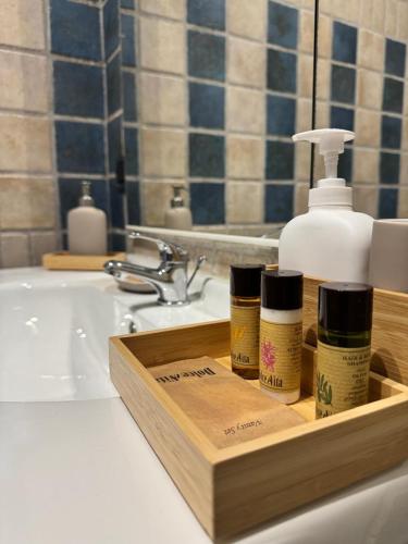 a bathroom sink with a wooden tray with three bottles of soap at Karol Beach House in Santa Marinella