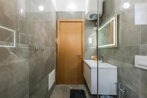 a bathroom with a sink and a wooden door at Exclusive Seafront Apartments Apartment 3 in Vlorë