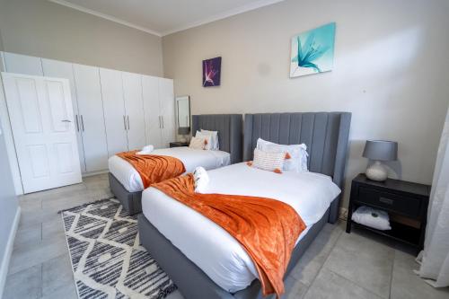 a bedroom with two beds with orange blankets at The Yard Platinum Peak, Victoria Falls in Victoria Falls
