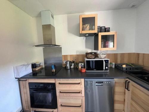 une petite cuisine avec une cuisinière et un micro-ondes dans l'établissement Maison bord de mer, équipée aménagée avec jardin, à Gueutteville-les-Grès