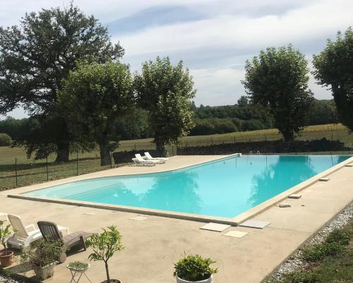 a large swimming pool with chairs and trees at Pîgeonnier du Rau avec Parc et piscine 1-0 in Gamarde-les-Bains