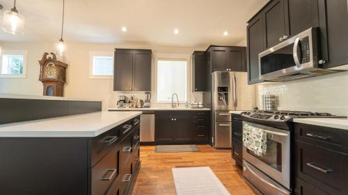 a kitchen with black cabinets and stainless steel appliances at Charming scape by Bear Mountain in Victoria