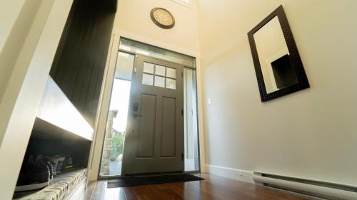 a hallway with a door and a clock on the wall at Charming scape by Bear Mountain in Victoria