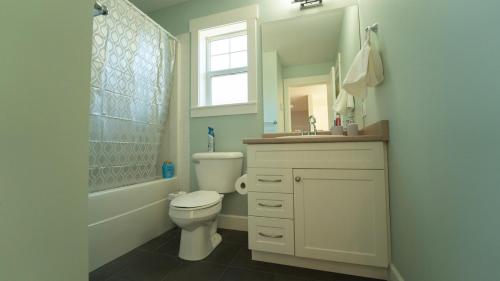 a bathroom with a toilet and a sink and a window at Charming scape by Bear Mountain in Victoria