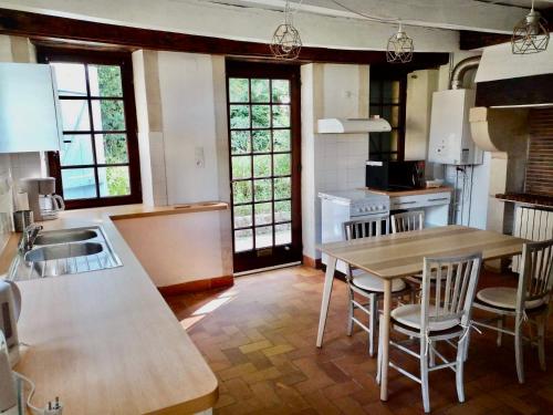 une cuisine avec une table et des chaises dans une cuisine dans l'établissement Pîgeonnier du Rau, à Gamarde-les-Bains