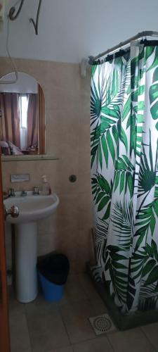 a bathroom with a sink and a shower curtain with leaves at Reconquista Villa Serrana in Villa Serrana