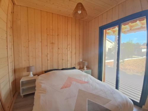 a bedroom with a bed and a large window at Cabane Alizée, Vensac Océan, Montalivet in Vensac