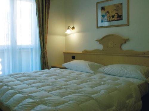 a bedroom with a large white bed with a window at Residence Pez Gajard in San Martino di Castrozza