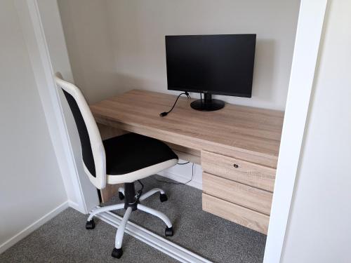 a computer desk with a monitor and a chair at Unwind Papamoa Beach - Papamoa Holiday Home in Papamoa