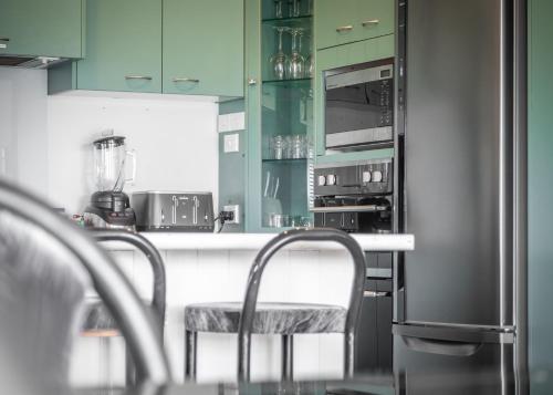 a kitchen with green cabinets and a counter with chairs at Mariri Heights Tasman in Upper Moutere