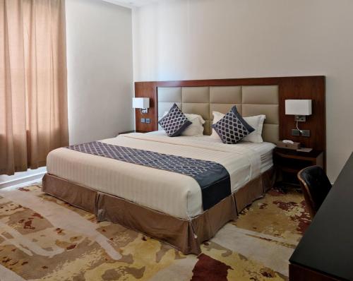 a bedroom with a large bed with blue and white pillows at دلتا جازان للوحدات الفندقية Delta Hotel Suites in Jazan