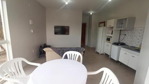 a white kitchen with a table and white chairs at Apartamento com Vista Panorâmica in São Gabriel
