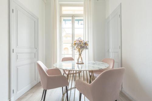 une salle à manger avec une table en verre et des chaises roses dans l'établissement Appartement Retro-chic proche de la mer, 4 à 6 personnes, à Nice