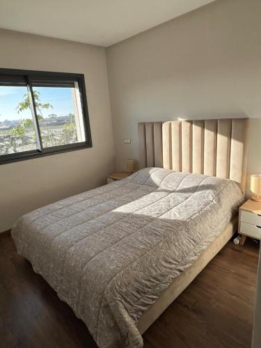 カサブランカにあるLuxury 2 bedroom flat in Tamaris Dar Bouazzaの大きなベッドと2つの窓がある寝室