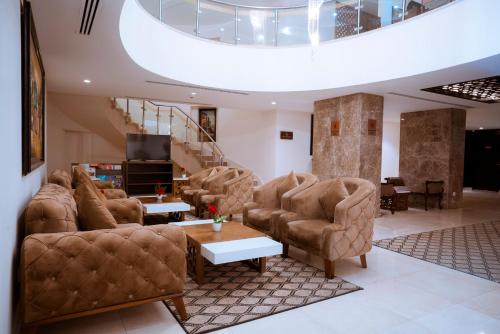 a living room with a couch and chairs and a tv at Rawa Luxury Hotel Suites in Amman