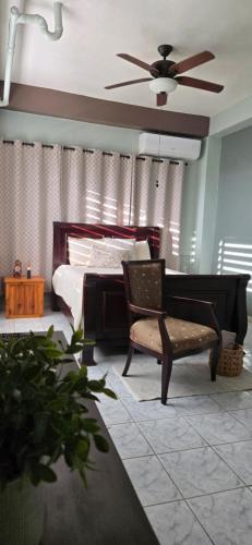 a bedroom with a bed and a chair and a ceiling fan at Casa Campo y mis Memorias-2ND LEVEL-with pool in Hormigueros
