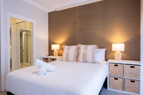 a bedroom with a large white bed and two lamps at 1BR Tropical Escape with Heated Pools Sauna BBQ in Gold Coast