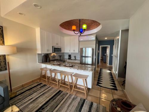a kitchen with white cabinets and bar stools at OCEAN VIEW GETAWAY! Penthouse Studio in Punta de Mita! in Punta Mita
