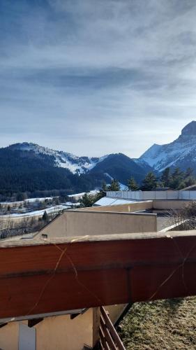 une vue d'un bâtiment avec des montagnes en arrière-plan dans l'établissement Charmant studio 5 personnes style montagnard, à Gresse-en-Vercors
