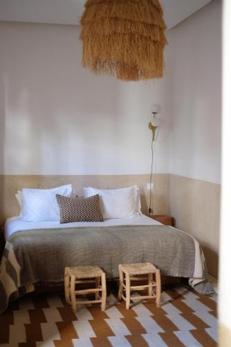 una camera da letto con un letto grande con due sgabelli sopra di Riad L'Atelier a Marrakech