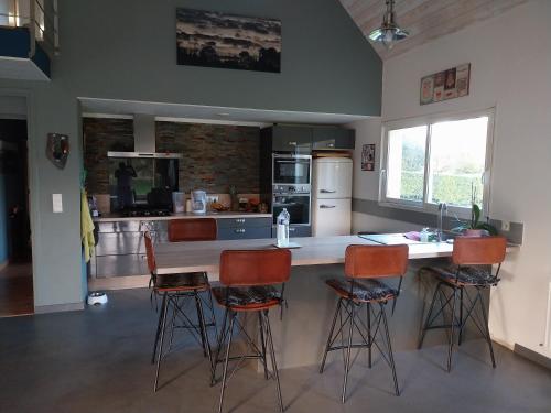 une cuisine avec un comptoir et des tabourets de bar dans l'établissement Maison très agréable, à Pleyber-Christ