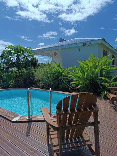 a wooden deck with a chair next to a swimming pool at Kaz a Klemence Gite creole avec piscine et table dhotes a Anse Bertrand in Anse-Bertrand