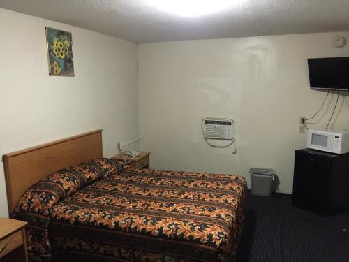 a hotel room with a bed and a tv at Hacienda Motel in San Jacinto