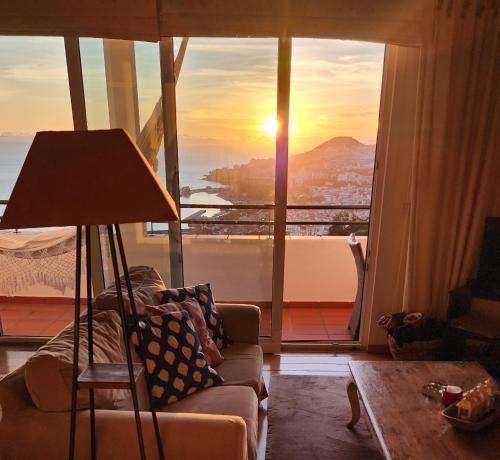 a living room with a couch and a lamp in front of a window at Murteiras Living in Funchal