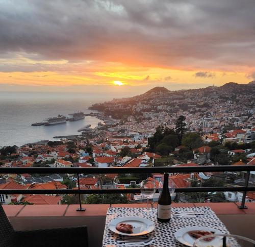 a table with a bottle of wine on a balcony with a view of the ocean at Murteiras Living in Funchal