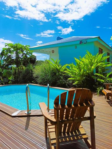 a wooden deck with a chair next to a swimming pool at Kaz a Klemence Gite creole avec piscine et table dhotes a Anse Bertrand in Anse-Bertrand
