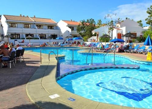 a large swimming pool with people sitting in chairs around it at Olimpus Apart Leasure in Costa de Adeje