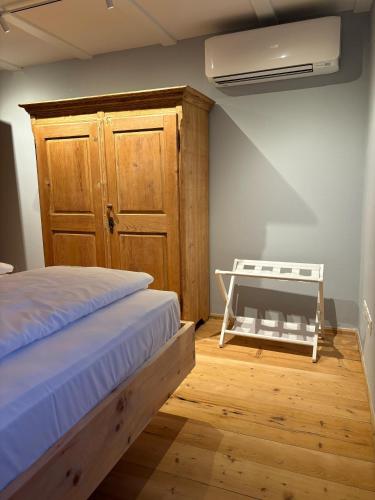 a bedroom with a bed and a wooden cabinet at ADAM Suites - Brixen Card included in Bressanone