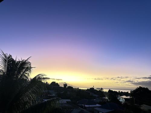 a sunset over a city with houses and the ocean at Ononui Airport Studio in Faaa