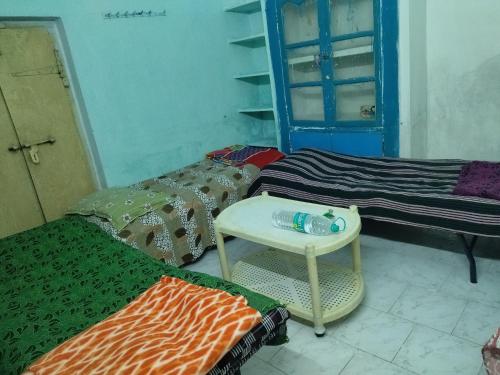 a room with two beds and a table and a chair at Sri kanakdhara homes in Vijayawāda