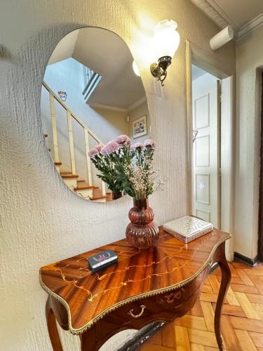 a vase of flowers on a table with a mirror at Hermosa casa en Barrio Pocuro con estacionamiento gratuito in Santiago