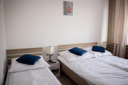 two beds in a bedroom with blue pillows on them at MyPlace Caramel Apartment Sandomierz in Sandomierz