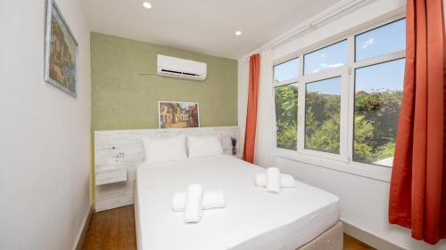 a bedroom with two white beds and a window at LİME BOZCAADA in Bozcaada