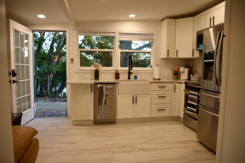 a kitchen with white cabinets and stainless steel appliances at Bamboo Bungalow - Waterfront Studio Near Beach in Cocoa Beach